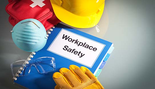 Workplace safety handbook with occupational safety equipment still life, a work training class and instruction manual for using safety equipment and administering first aid. Employment education document with protective eyewear, hard hat, first aid kit, work glove, and pollution mask. Guidance and planning tools in horizontal format with copy space.