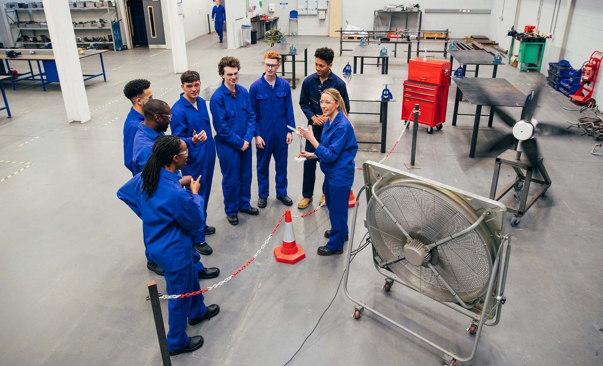 Apprentices in overalls stood around listening to their teacher